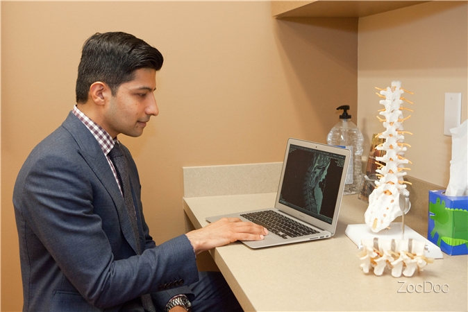 Dr. Khan reviewing a spinal x-ray on a silver laptop